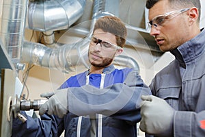 engineer advising apprentice in factory front view close up