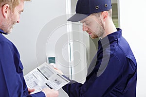 Engineer and apprentice adjusting thermostat for efficient automated heating system