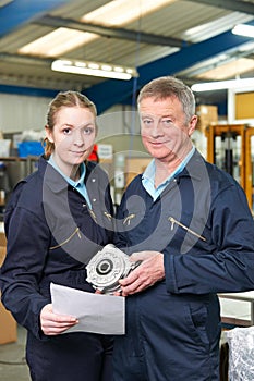 Engineer And Apprentice With Component In Factory