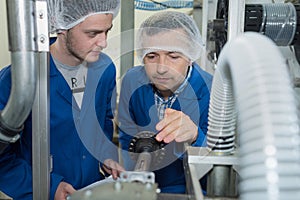 Engineer and apprentice discussing component in factory