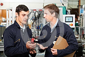 Engineer And Apprentice Discussing Component In Factory
