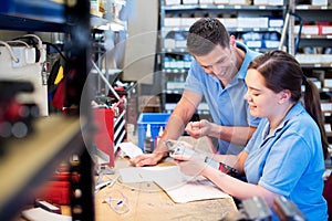 Engineer And Apprentice Examining Component At Workbench