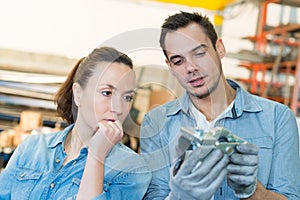 engineer and apprentice looking at component in factory