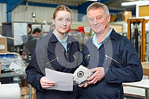 Engineer With Apprentice Looking at Component In Factory