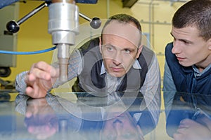 Engineer and apprentice using automated milling machine