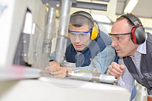 Engineer and apprentice using automated milling machine