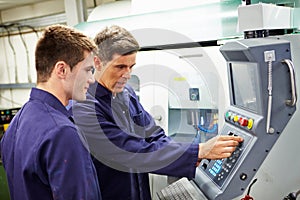 Engineer And Apprentice Using Automated Milling Machine