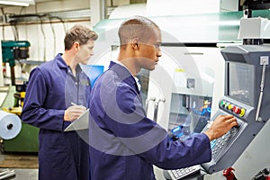 Engineer And Apprentice Using Automated Milling Machine