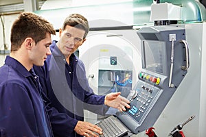 Engineer And Apprentice Using Automated Milling Machine