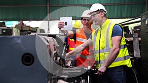 Engineer And Apprentice Using Automated Milling Machine. Worker with goggles and helmet on the machine