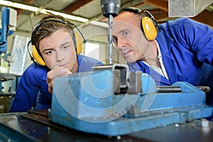 Engineer with apprentice using bench drill