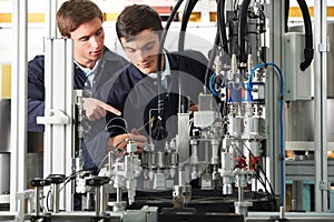 Engineer And Apprentice Working On Equipment In Factory