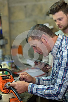 Engineer and apprentice working on machine in factory