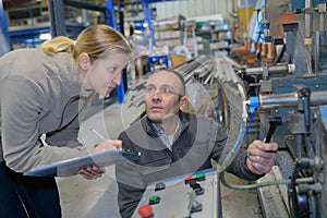 engineer and apprentice working on machine in factory