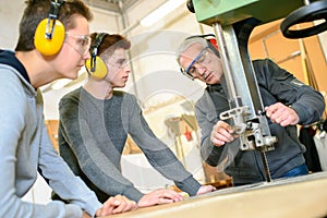 Engineer and apprentices using automated milling machine