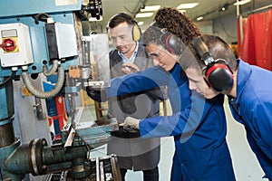 engineer and apprentices working on machine in factory