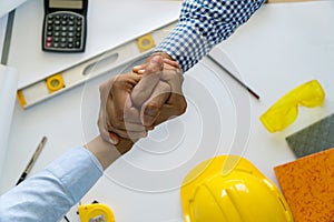 Engineer Architect concept. Two construction engineers finished working shaking hands on table office with blueprints