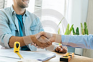 Engineer, architect, construction worker team hands shaking after plan project contract on workplace desk in meeting room office a