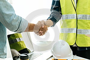 Engineer, architect, construction worker team hands shaking after plan project contract on workplace desk in meeting room office a