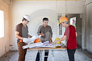 Engineer and architect discussing with foreman about project in building construction site