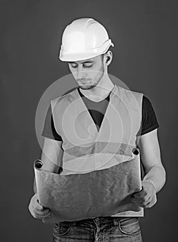 Engineer, architect, labourer, builder on strict face holds old blueprint in hands. Engineering concept. Man, handyman