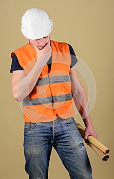 Engineer, architect, labourer, builder on thoughtful face holds old blueprints in hand. Man, foreman in helmet, hard hat