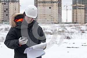 Engineer or Architect with protective safety helmet checking architectural drawing calling support team at construction