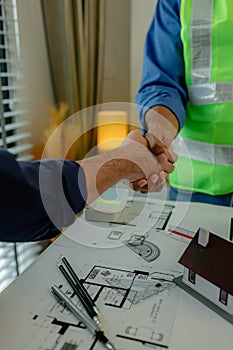 engineer and architect are shaking hands to celebrate because they just finished big construction project, two engineers do