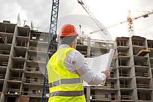 Engineer on building site examines blueprints