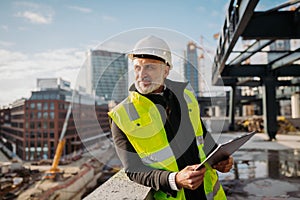 Engineer checking building documentation on clipboard at construction site.
