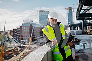 Engineer checking building documentation on clipboard at construction site.
