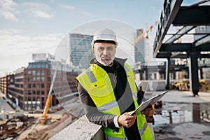Engineer checking building documentation on clipboard at construction site.