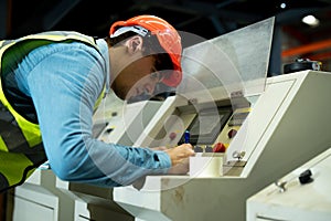 The engineer is checking and inspecting at the factory. He is working with the laptop to check range of votage