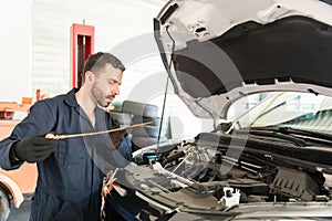 Engineer Checking Oil Level In Car Engine At Workshop