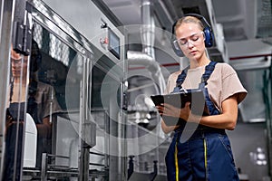 engineer checking robotic line for bottling and packaging pesticides into canisters, take notes