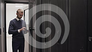 IT engineer checking routers in server room using a phone