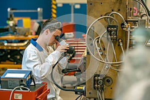 The engineer checks the correct setting of the metal mold for castings in the factory using a microscope