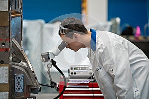 The engineer checks the correct setting of the metal mold for castings in the factory using a microscope