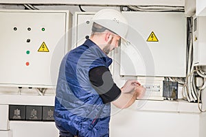 Engineer checks the electrical supply system.  The specialist works with powerful electric boxes. A technician turns off