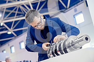 Engineer checks quality of crankshaft for engine at car manufacturing plant