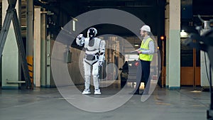 An engineer checks a robot working, using a tablet.