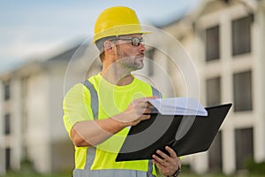 Engineer with clipboard, building inspection. Builder on site construction. Man worker in hard hat. Construction worker