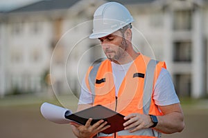 Engineer with clipboard, building inspection. Caucasian man, construction worker in helmet at construction site