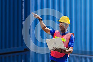 Engineer with clipping path in hard hat and safety vest holding a laptop, Factory worker man at container cargo