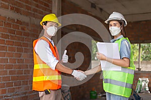 Engineer concept The male engineering worker who wears oranges uniform shaking hand with the female worker who wears green uniform
