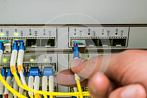 The engineer connects the optical Internet cable with the central router module in the server room of the data center. The front