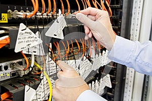 Engineer connects optical patchcords to switches in data center. Telecommunications in data center. Fiber