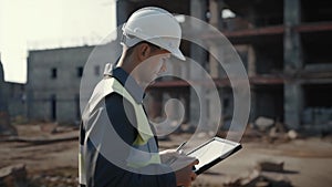 An engineer at a construction site in a white helmet with a tablet