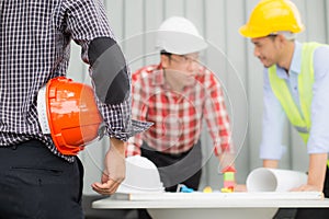 Engineer and construction team wearing safety helmet and looking blueprint on the table