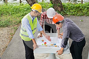 Engineer and construction team wearing safety helmet and looking blueprint on the table.